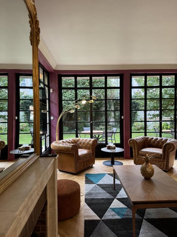 a living room with a fireplace and furniture and windows at Erawan Boutique Hôtel in Évreux