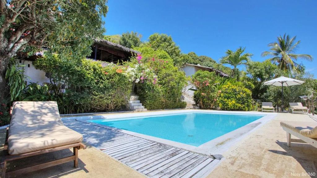 a swimming pool with a chair and a house at Villa Razambe in Mandriankeniheny