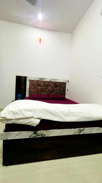 a bedroom with a large bed with white sheets and red pillow at Hotel Maa Bhagvati in Orchha