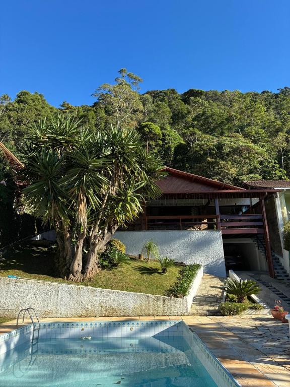a swimming pool in front of a house with a tree at Casa Au Clair de Lune Terê in Teresópolis