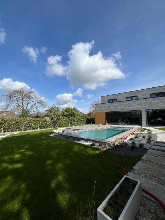 a large yard with a swimming pool in front of a building at Executive Villa with pool in Londerzeel