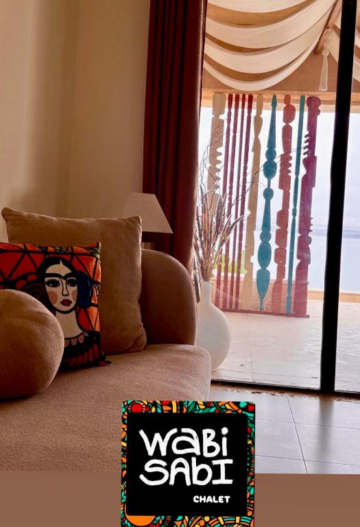 a living room with a couch with a pillow and a window at Samarah EP 04 full Sea View and poll access prime location with big terrace, in Sowayma