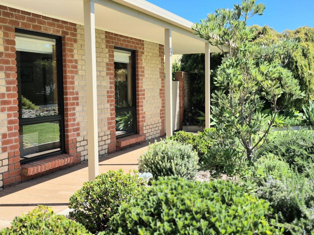 a brick house with a garden of bushes at Relax on Ryan Robe - 100m to Beach, Cafes and Town in Robe