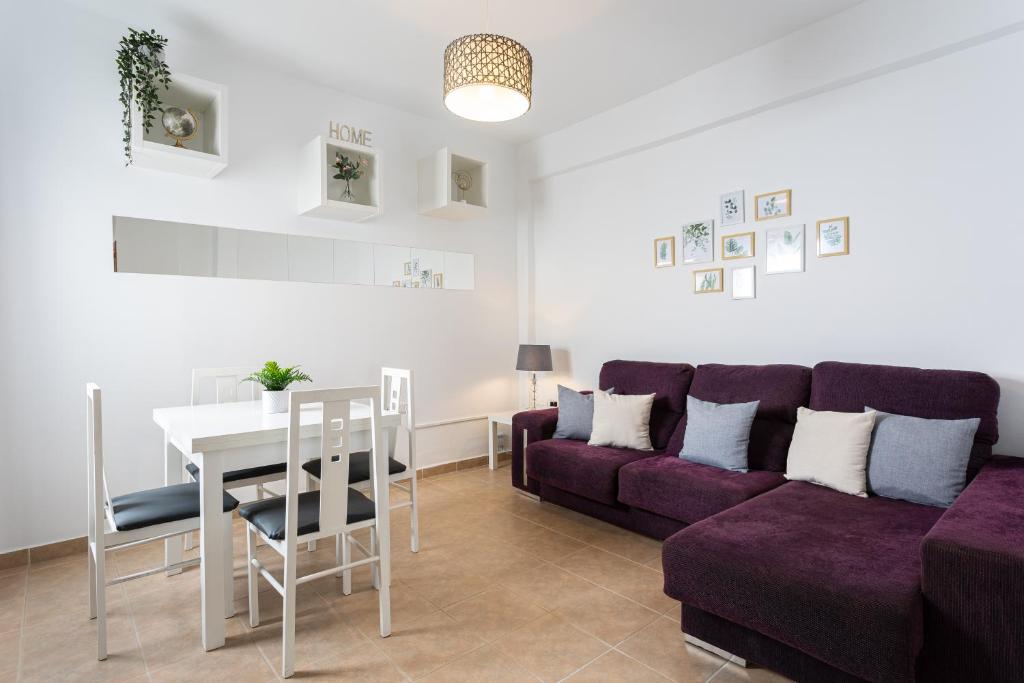 a living room with a purple couch and a table at Apartamento Los Angeles Cerca Estación Tren Aeropuerto in Málaga