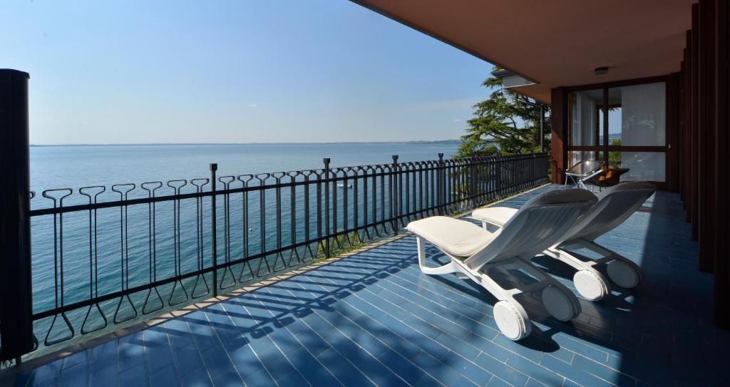 una silla blanca sentada en un balcón con vistas al océano en Holiday Garda Villa Dolcelago Lake Front, en Moniga del Garda