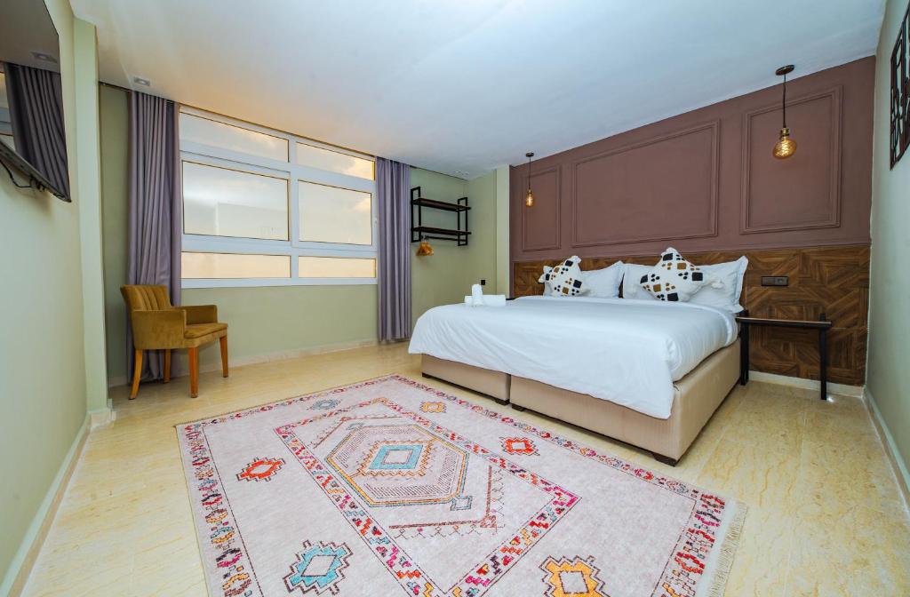 a bedroom with a large bed and a rug at Singular Hotel, SH Dakhla in Dakhla