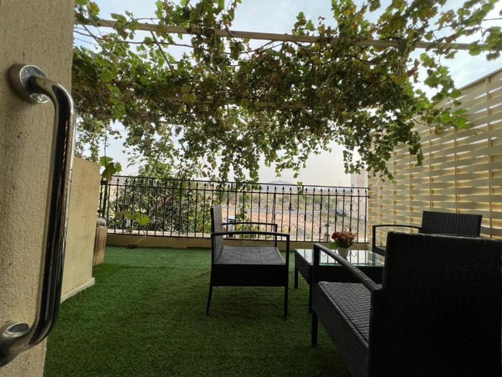 a balcony with a table and chairs and a tree at شقةكبيرة 4 غرف نوم وصالة بلكونه Large apartment with 4 bedrooms, a living room and a balcony in Taif
