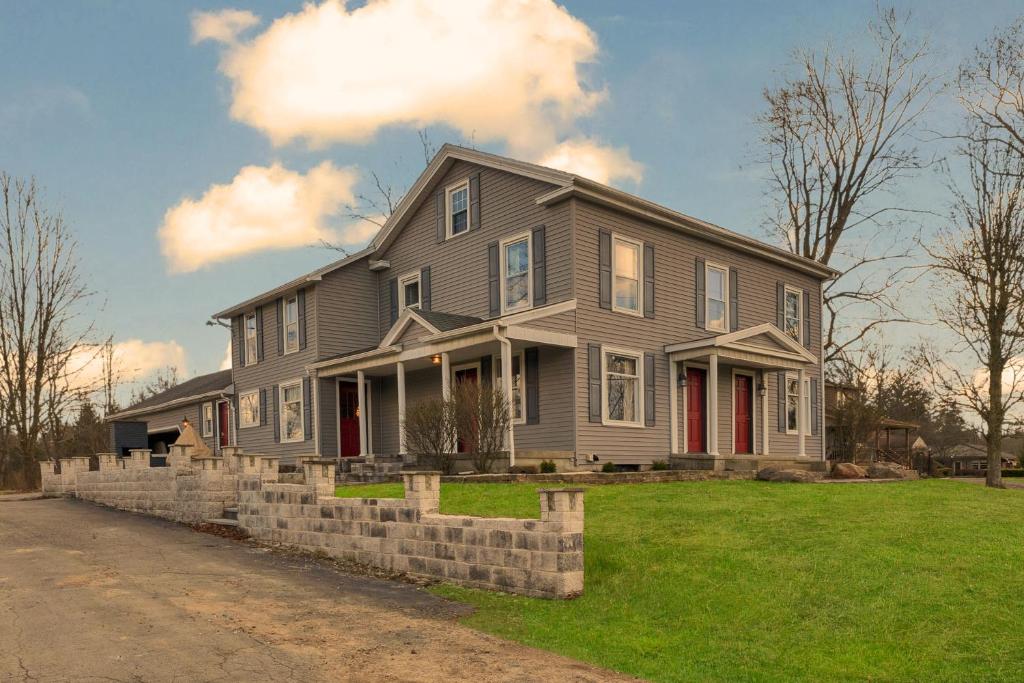 a gray house with red doors on a green yard at The John Collins House in Canfield