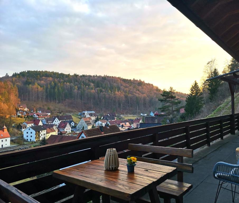 a wooden table on a balcony with a view of a town at Haus Sommerseit'n Ruhe-Natur-Genuss in Hirschbach