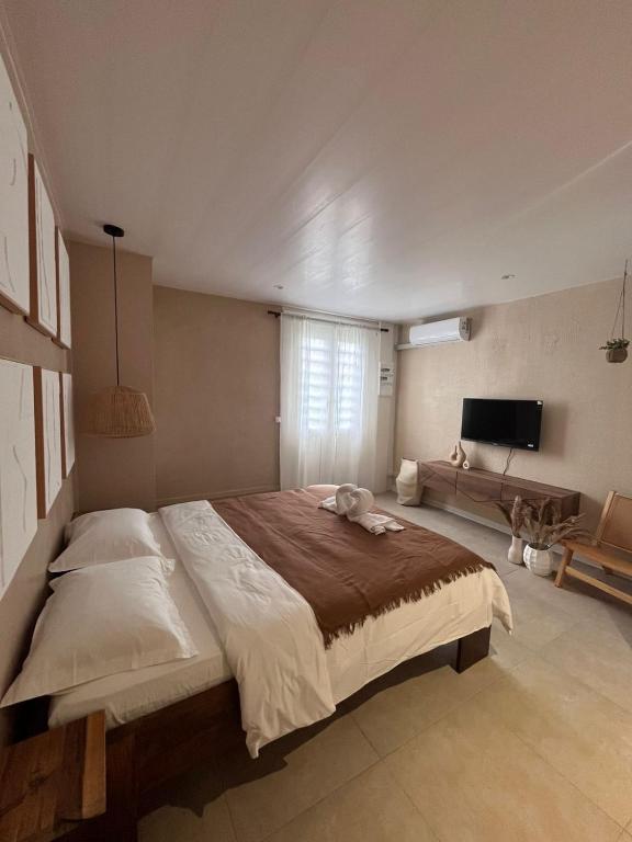 a bedroom with a large bed and a television at Studio Tulum - jacuzzi privé - face à la mer in Tartane