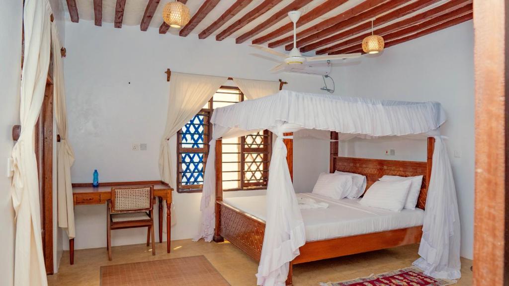 a bedroom with a canopy bed and a desk at AMOODY MANZIl in Shela