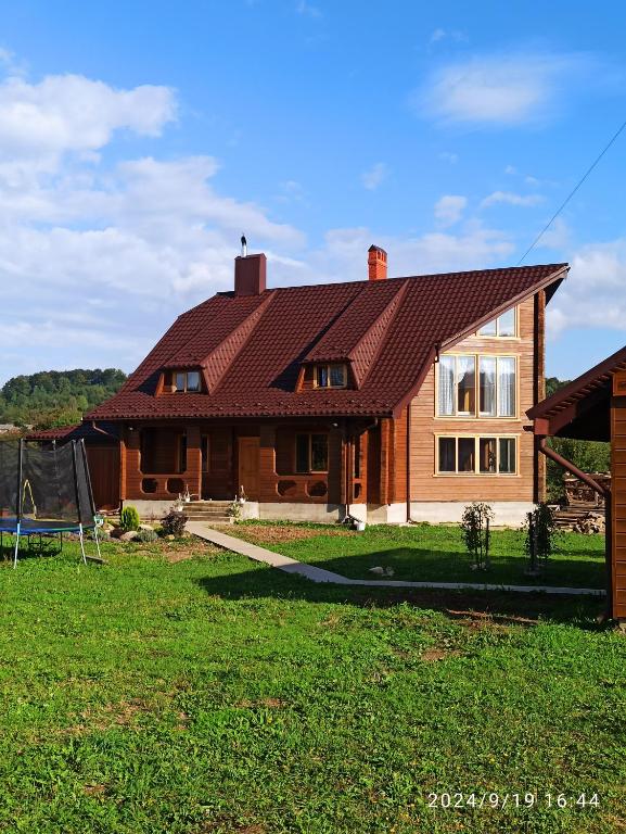 a house with a red roof on a green yard at Садиба Буквиця in Migovo