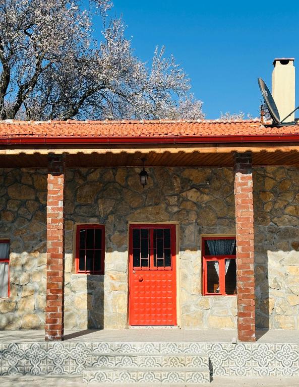 a brick building with a red door and three windows at Pergamon Yunt Evleri in Bergama