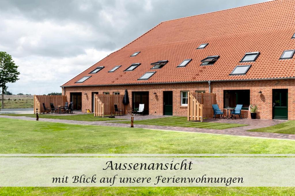 a building with a red roof with windows at Ferienwohnung Frieda - Gulfhof nahe Greetsiel mit Sauna, Garten & 3 Schlafzimmern in Krummhörn