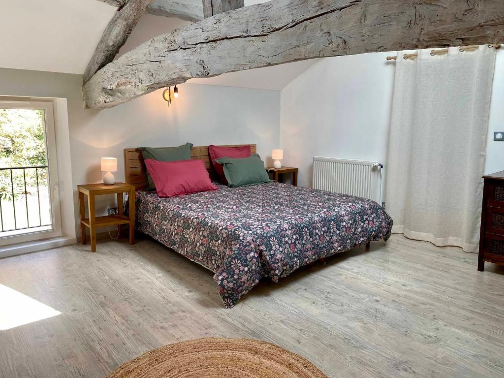 a bedroom with a bed and two tables and a window at Le chant des Loriots in Bajamont