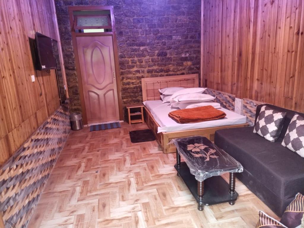 a room with a bed and a couch and a door at Sai Palace in Darjeeling