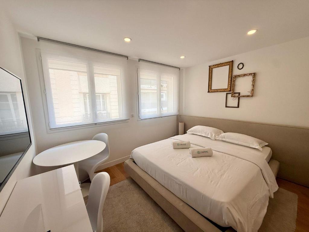a bedroom with a bed and a table and two windows at B044 Studio moderne Croisette 100m in Cannes