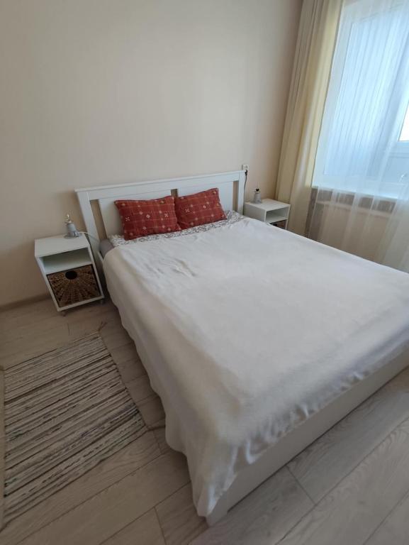 a bedroom with a large white bed with red pillows at Rinktinės apartments in Vilnius