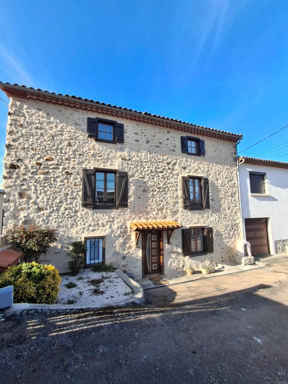 a stone house with black windows and a door at Gite Familial aux portes de Foix "Le Coulhòu"- Ariège- 6 personnes in Ferrières-sur-Ariège