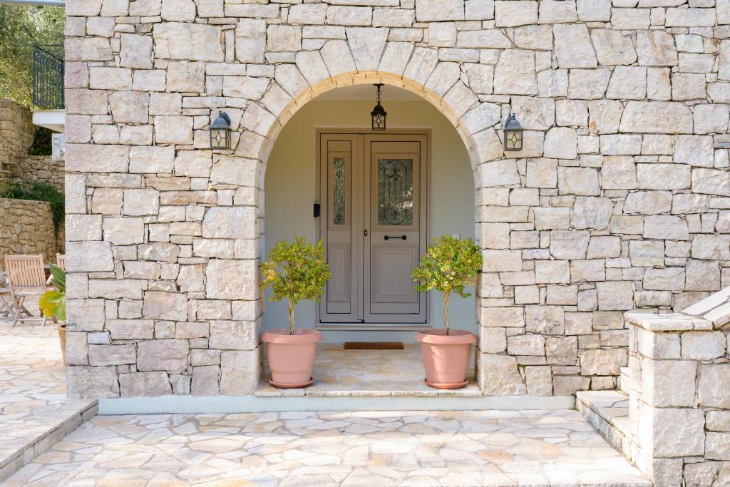 an entrance to a stone house with two potted plants at Fereniki's place in Gaios