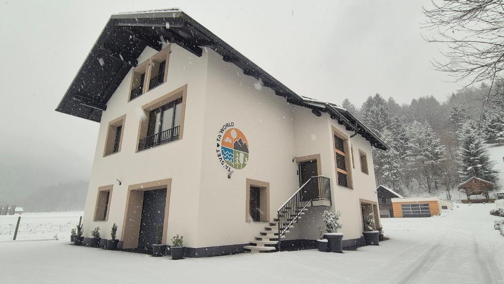 a building in the snow with snow covered ground at Ta World apartments in Spodnji Log