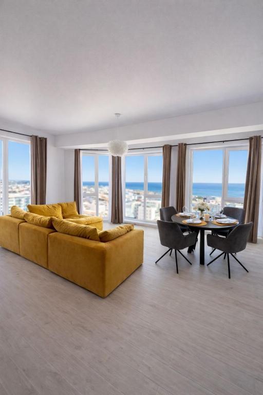 a living room with a yellow couch and a table at Apartament Meraki SeaView in Mamaia Sat/Năvodari