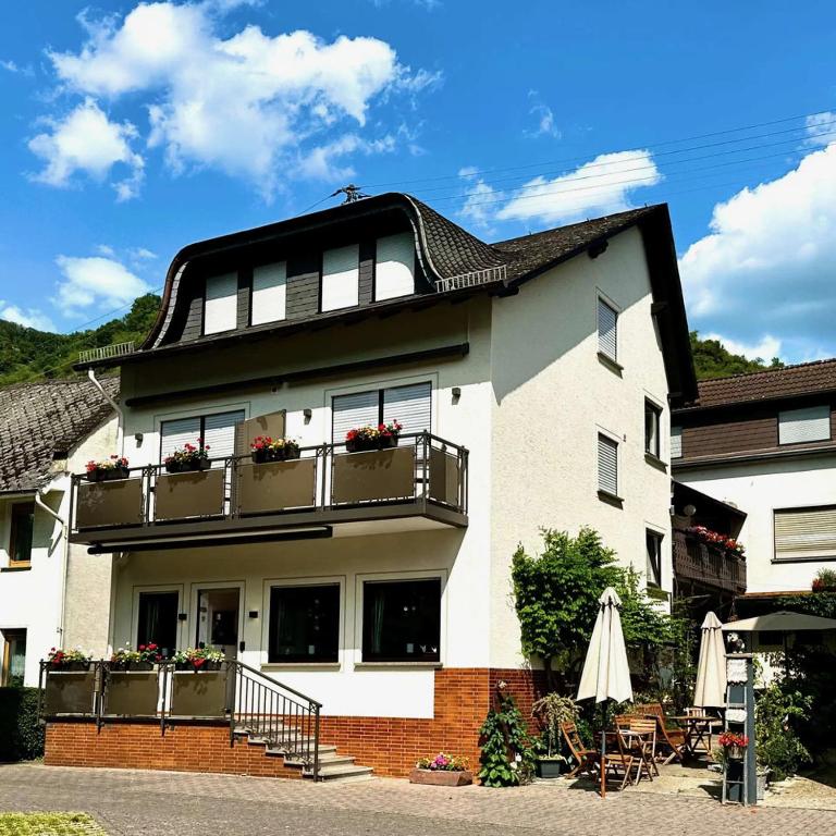 a large white house with balconies and a patio at Pension / Ferienwohnungen Scheid in Kestert