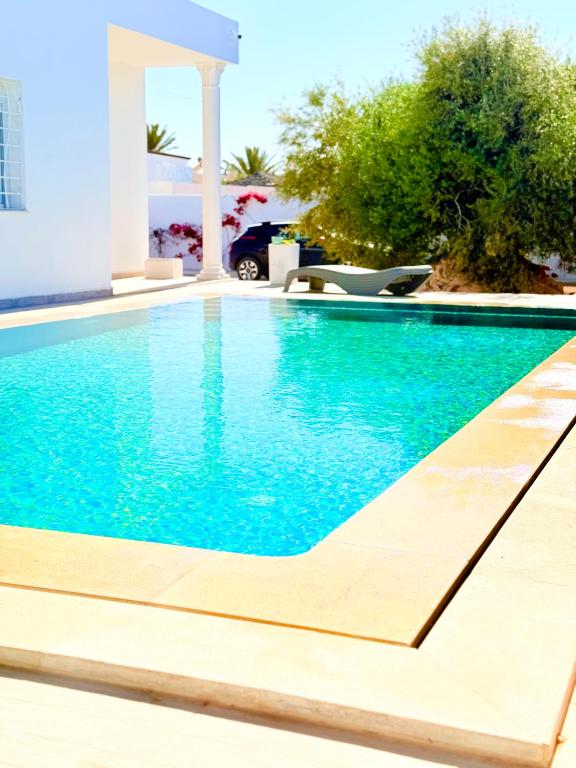 a swimming pool in a villa with blue water at Résidence Azur Djerba in Taguermess