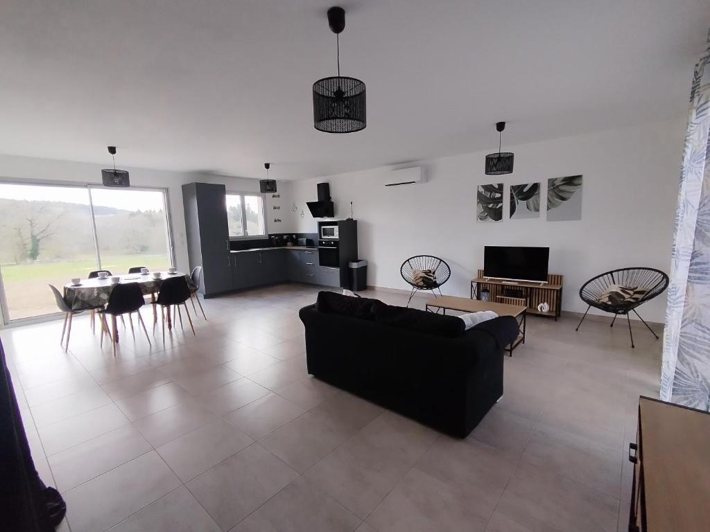 a living room with a black couch and a table at Maison Saint-Pardoux in Friaudour