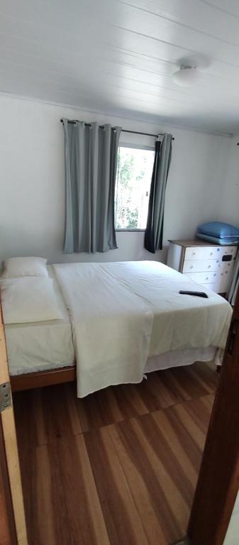 a bedroom with a large white bed with a window at Chalé da Helô in Nova Friburgo