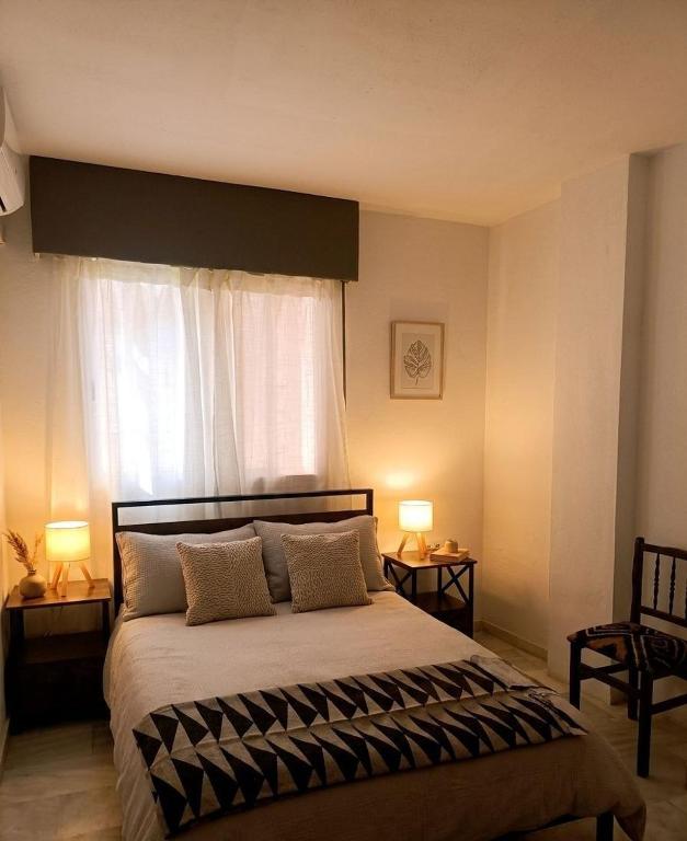 a bedroom with a bed with two lamps and a window at Forrent malaga in Málaga