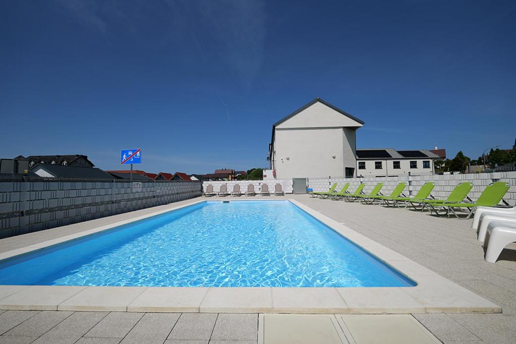 a swimming pool with lounge chairs and a church at Sofia Domki Wakacyjne Dwupoziomowe in Jarosławiec