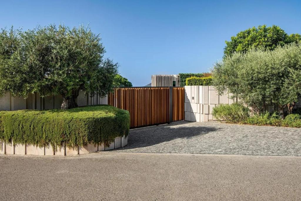 a fence with a hedge and a gate with trees at Rose Bank in Johannesburg