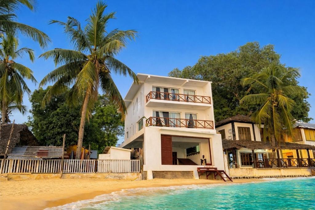 a white house on the beach next to the water at Villalola in Nosy Be