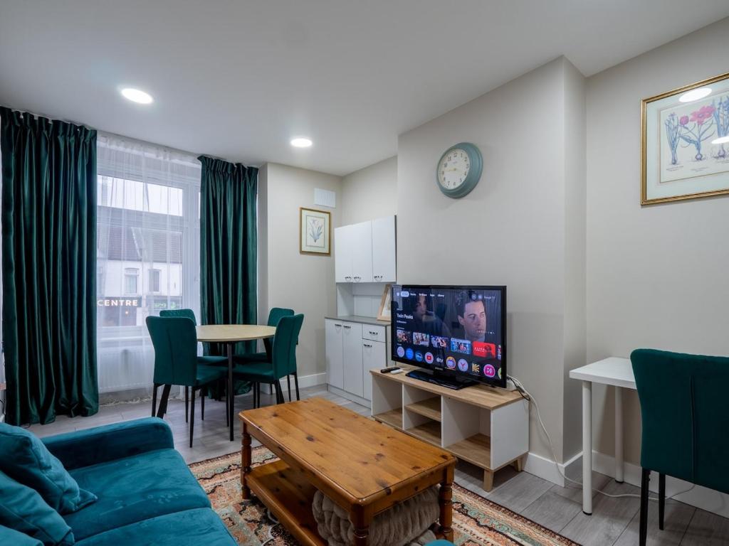 a living room with a couch and a tv and a table at Spacious 2-Bedroom Flat in Worcester Park
