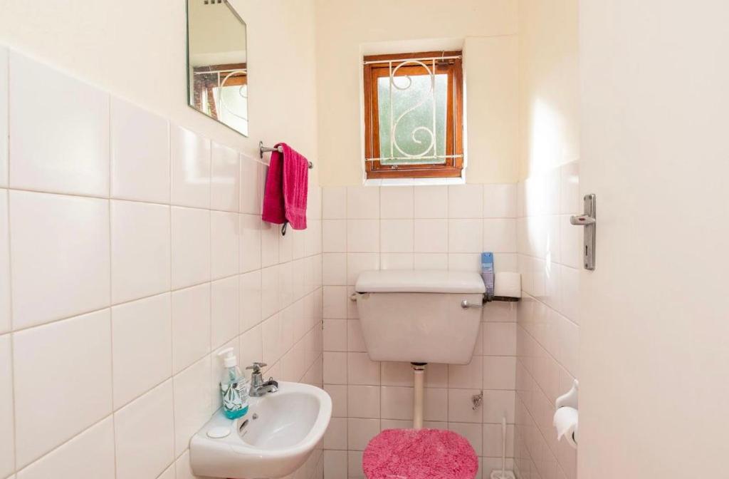 a white bathroom with a toilet and a sink at Sunset Nest in Meadowridge