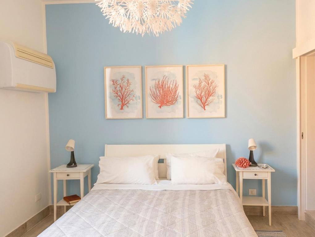 a bedroom with a bed with four paintings on the wall at La Piazzetta in Syracuse