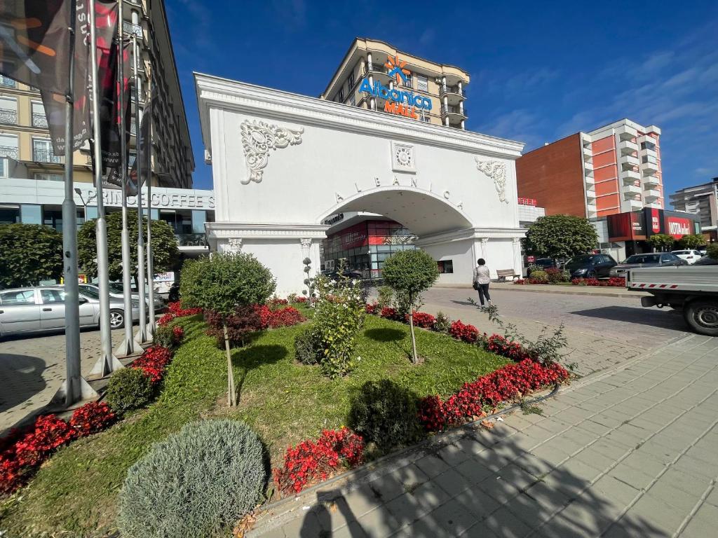 a white building with a flower garden in the street at Sonny Penthouse 2 in Gnjilane