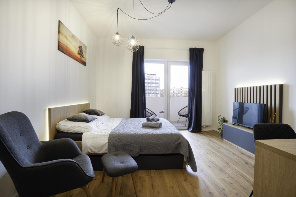 a bedroom with a bed and a chair and a tv at Calmora apartment Optická WiFi Klimatizace Balkon Nespresso in Komárov