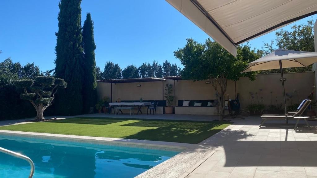 a backyard with a pool and a table and an umbrella at Casa Las Fatiguitas al lado de Torrijos y muy cerca de Toledo y de Puy du Fou in Caudilla