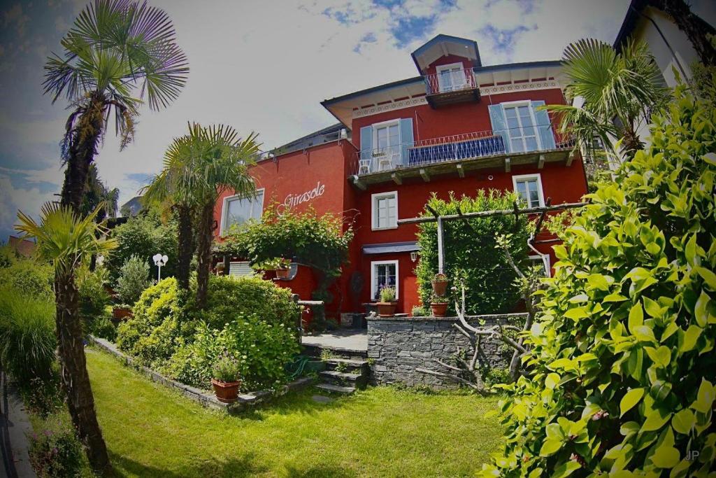 a red house with a palm tree in front of it at Girasole Orselina in Orselina