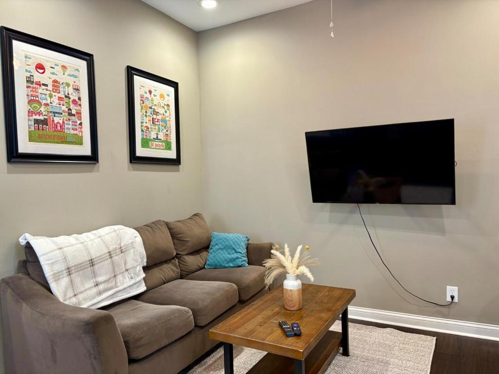 a living room with a couch and a tv on the wall at Cozy Gem Mins from U of L Hospital & Downtown in Louisville