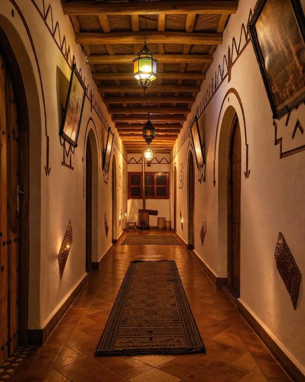 a hallway with arches and a rug on the floor at Auberge des peupliers Café Restaurant in Akhendachou nʼAït Ouffi