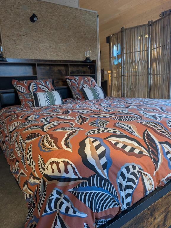 a large bed with a colorful comforter and pillows at Chic and Chill Guest House, gite Safari in Vallon-Pont-dʼArc
