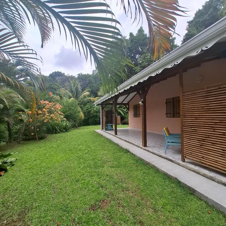 a house with a blue bench next to a yard at VILLA Ti-COULANGE, Verdoyante in Rivière-Pilote