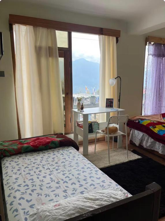 a bedroom with a bed and a desk and a window at Lhamus homestay in Tawang