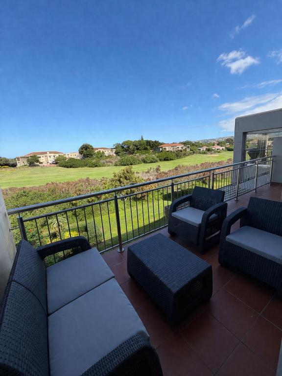 a patio with couches and chairs on a balcony at Goose Valley Golf Estate D7 in Plettenberg Bay