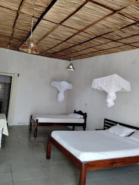a room with two beds and two tables in it at Pirogue D'or in Morombe
