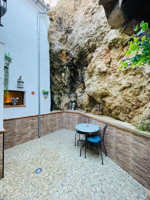 a table and chairs in front of a rock wall at Casa Isabel in El Gastor
