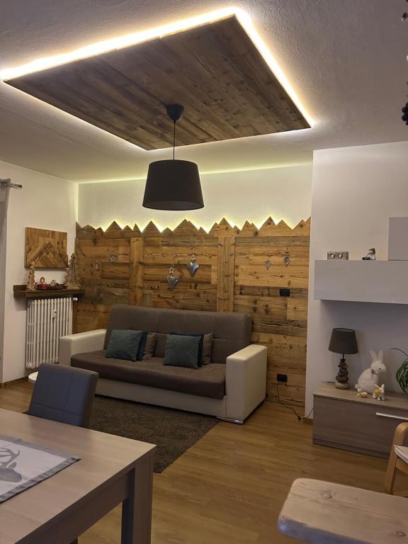 a living room with a couch and a wooden wall at Appartamento "Roby" in centro Cavalese in Cavalese